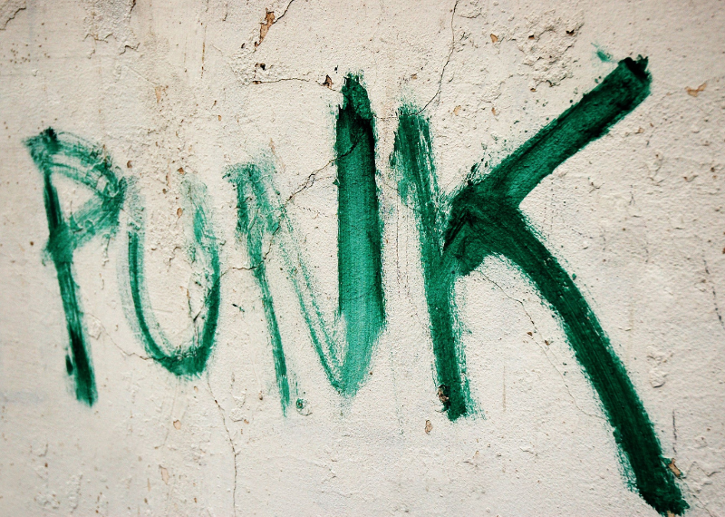 Green graffitti on white wall saying punk